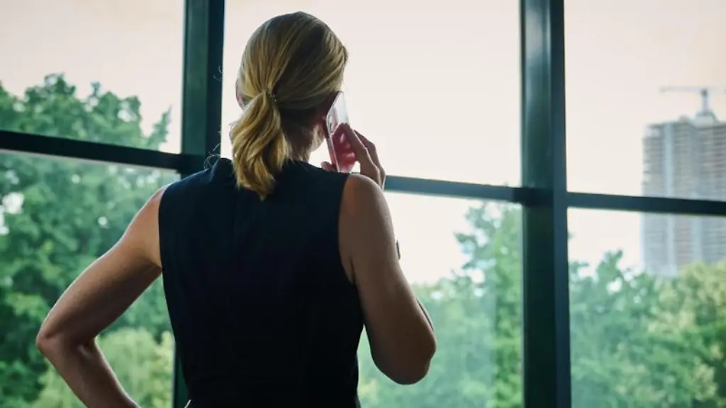 Eine-Frau-steht-in-einem-Buerozimmer-am-Fenster-und-telefoniert