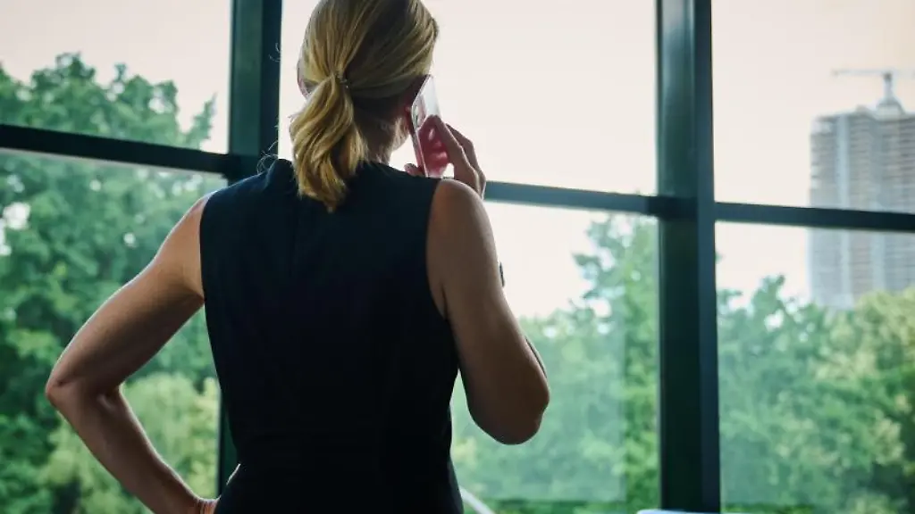 Eine-Frau-steht-in-einem-Buero-am-Fenster-und-telefoniert