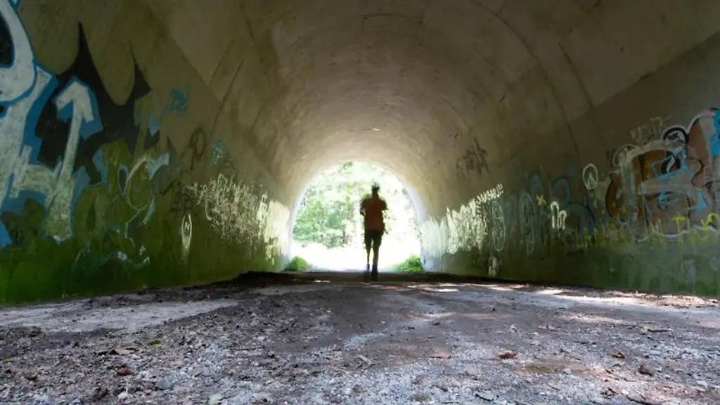 Ein-Passant-geht-durch-eine-Unterfuehrung-die-mit-Graffiti-besprueht-ist