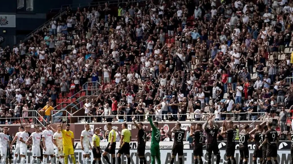 Die-Spieler-beider-Mannschaften-begruessen-die-Zuschauer-im-Stadion