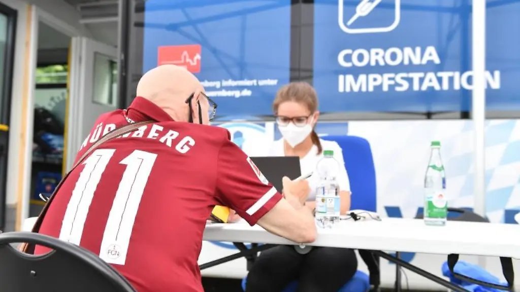 Ein-Fan-vom-1-FC-Nuernberg-fuellt-vor-dem-Spiel-gegen-Erzgebirge-Aue-an-einem-Impfbus-ein-Formular-zur-Impfung-gegen-Covid-19-aus