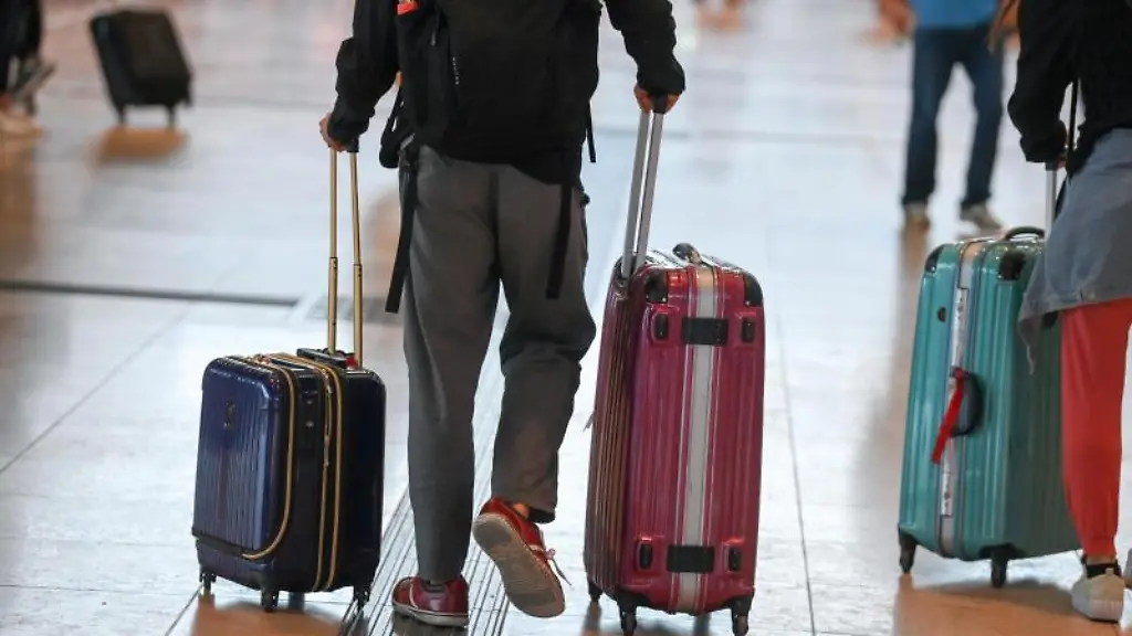 Reisende-gehen-im-Flughafen-Berlin-Brandenburg-BER-mit-Koffern-durch-den-Abflugsterminal