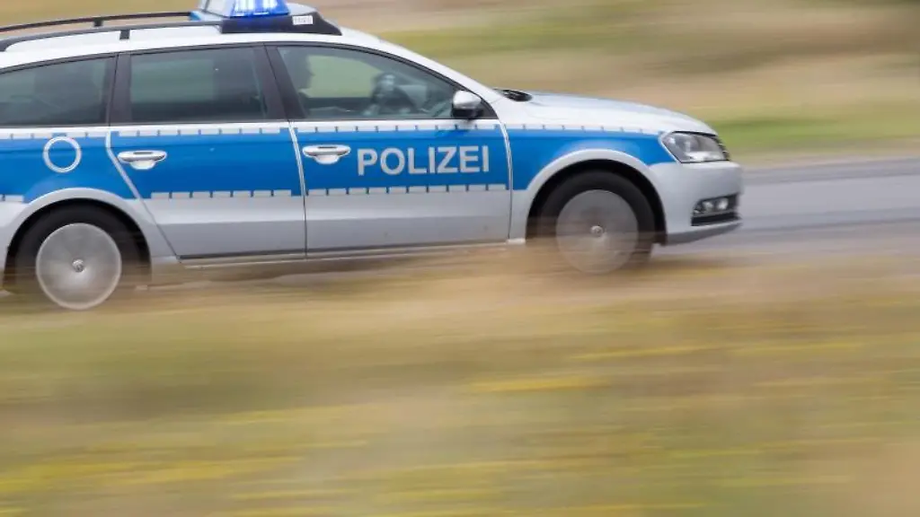 Ein-Polizeifahrzeug-faehrt-mit-Blaulicht-auf-der-Landstrasse