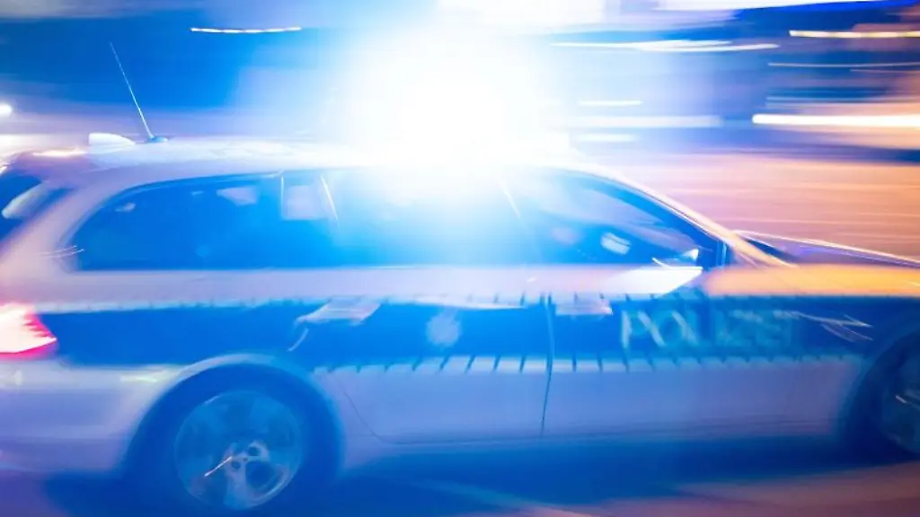 Ein-Polizeiauto-faehrt-mit-Blaulicht-ueber-eine-Strasse