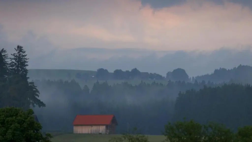 Eine-Holzhuette-steht-im-Abendlicht-in-der-wolkenverhangenen-Allgaeuer-Landschaft
