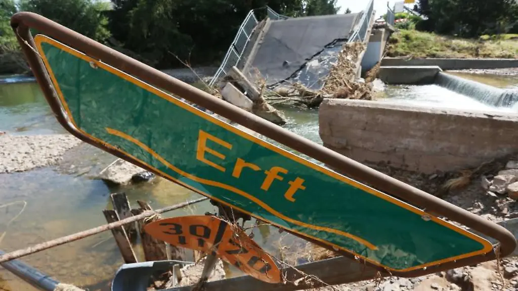 Ein-Hinweisschild-auf-die-Erft-liegt-vor-einer-zerstoerte-Bruecke-im-Schutt