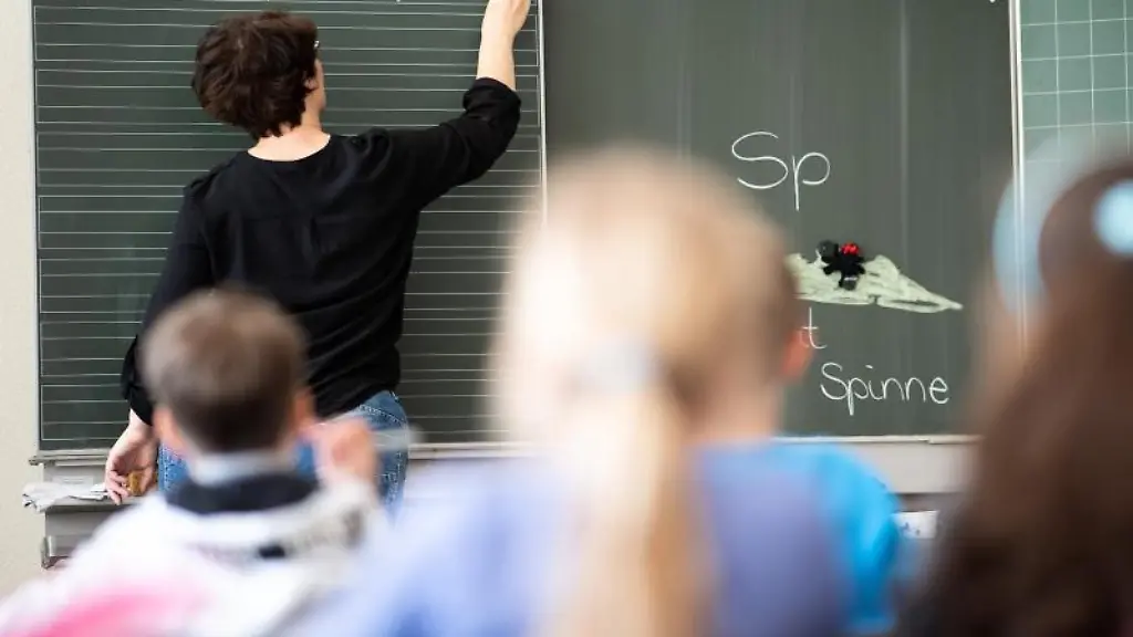 Eine-Lehrerin-schreibt-in-einer-Grundschule-Woerter-mit-Sp-am-Anfang-auf-eine-Tafel
