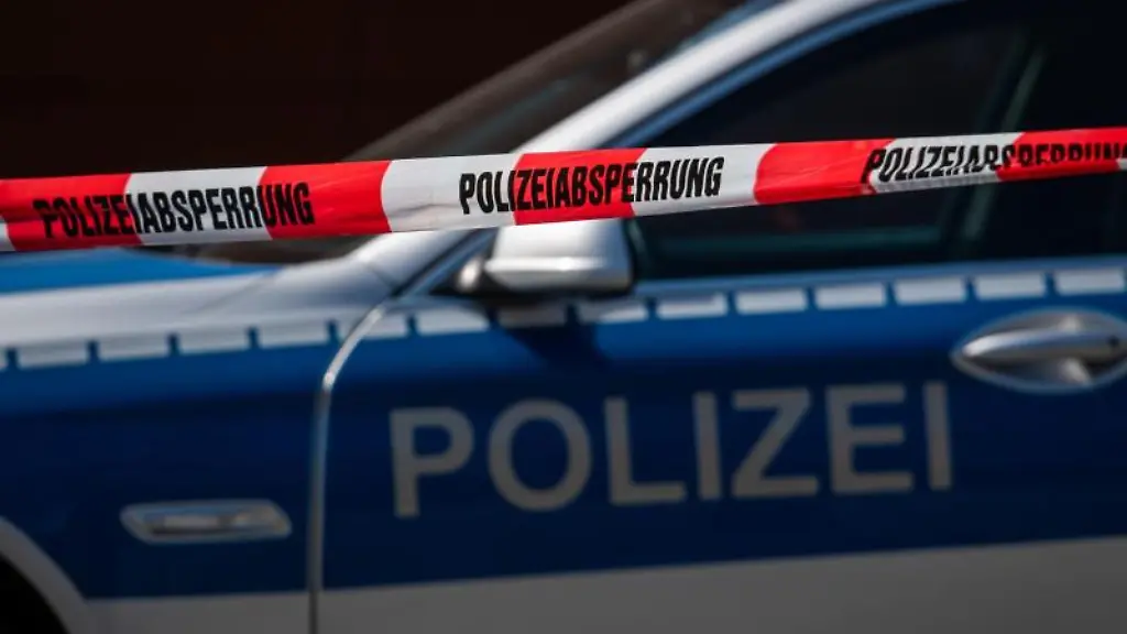 Ein-Polizeiauto-steht-hinter-einem-Absperrband-der-Polizei