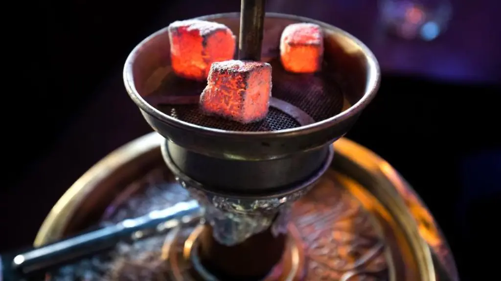 Gluehende-Kohle-liegt-auf-einem-Metallsieb-ueber-dem-Tabak-im-Kopf-einer-Wasserpfeife-in-einer-Shisha-Bar