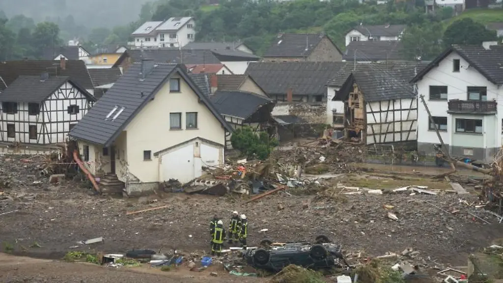 Feuerwehrleute-stehen-in-der-Gemeinde-Schuld-am-Tag-nach-der-Hochwasserkatastrophe-in-Truemmern