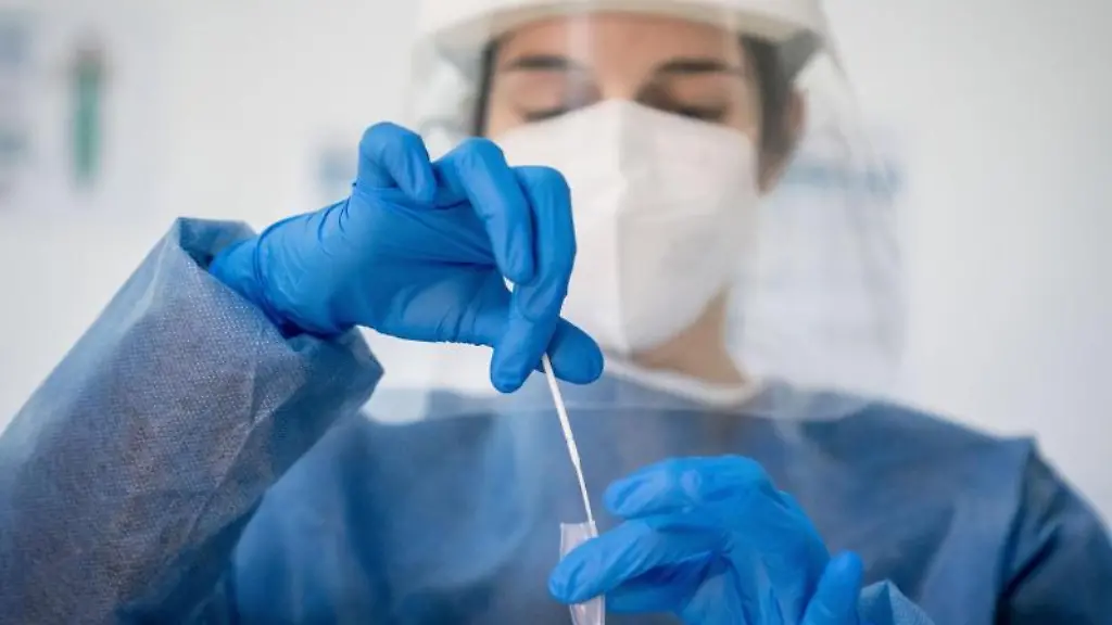 Medizinisch-geschultes-Personal-legt-das-Wattestaebchen-von-einem-Corona-Schnelltest-in-eine-Loesung