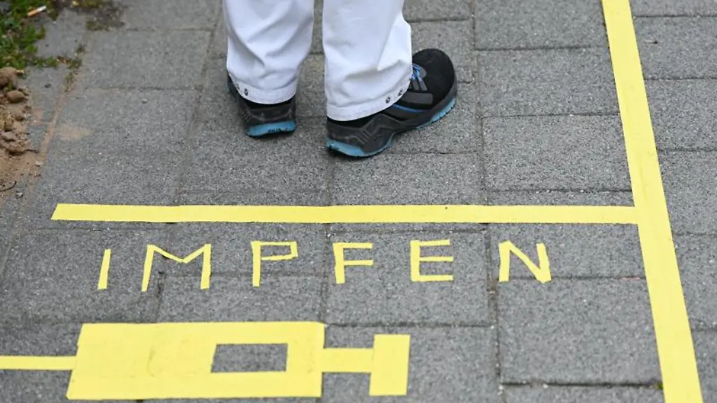 Ein-Mann-steht-an-einem-Covid-19-Impfcenter-hinter-der-Bodenaufschrift-Impfen
