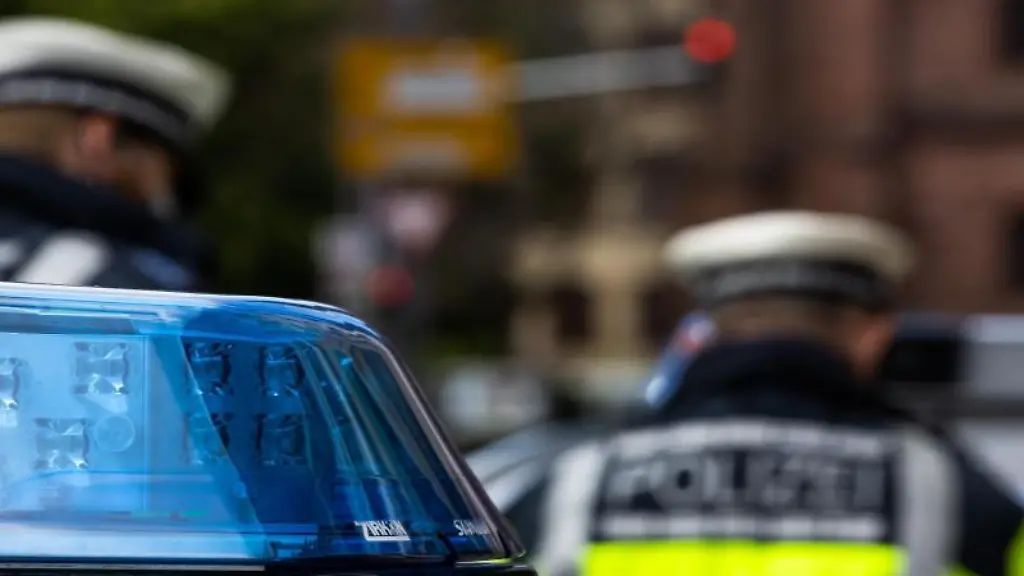 Zwei-Polizeibeamte-stehen-zwischen-Einsatzfahrzeugen