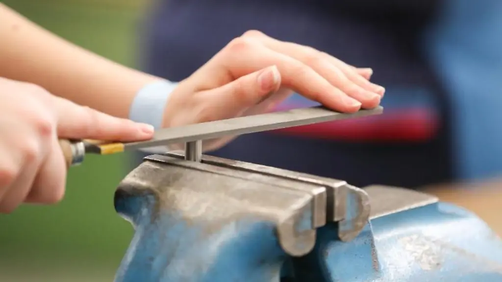 Eine-weibliche-Auszubildende-feilt-an-einem-Werkstueck