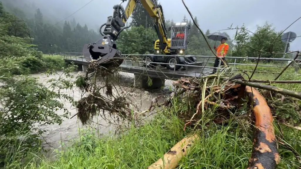 Mit-schwerem-Geraet-wird-angeschwemmtes-Holz-aus-der-Stillach-bei-Oberstdorf-gehoben