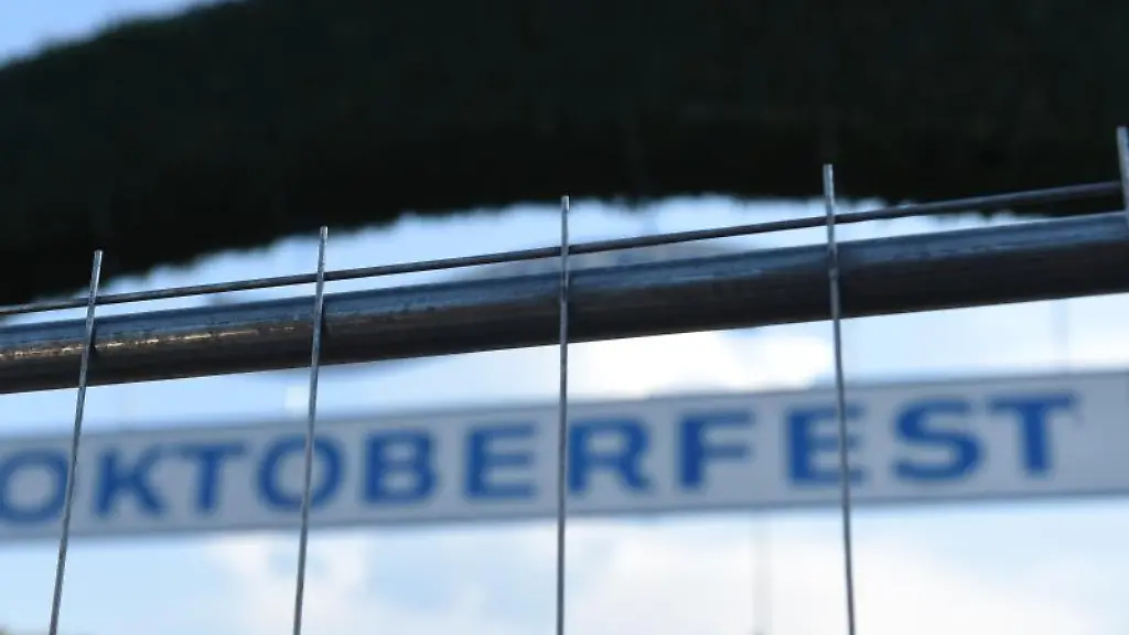 Der-Schriftzug-Oktoberfest-ist-am-Haupteingang-der-Wiesn-hinter-einem-Metallzaun-zu-sehen