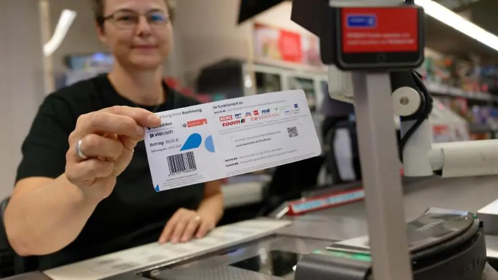 Eine-Mitarbeiterin-in-einer-Filiale-des-Einzelhaendlers-Rewe-haelt-ein-Blatt-mit-einem-Barcode-in-der-Hand