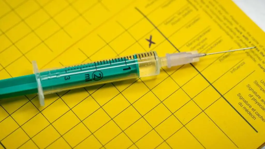 Eine-Spritze-liegt-auf-einem-Impfpass