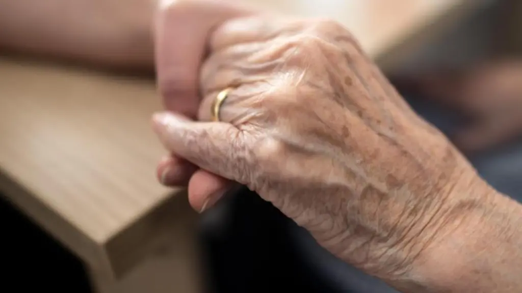 Eine-Pflegerin-haelt-die-Hand-einer-alten-Frau-in-einem-Altenheim