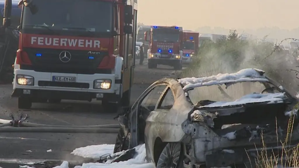 Die-Feuerwehr-steht-hinter-dem-ausgebrannten-Wrack-eines-Autos-auf-der-A3