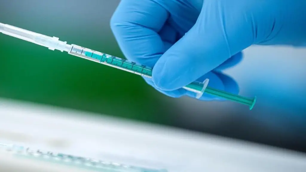 Ein-Mitarbeiter-vom-Impfzentrum-haelt-eine-Spritze-mit-dem-Covid-19-Impfstoff-in-der-Hand