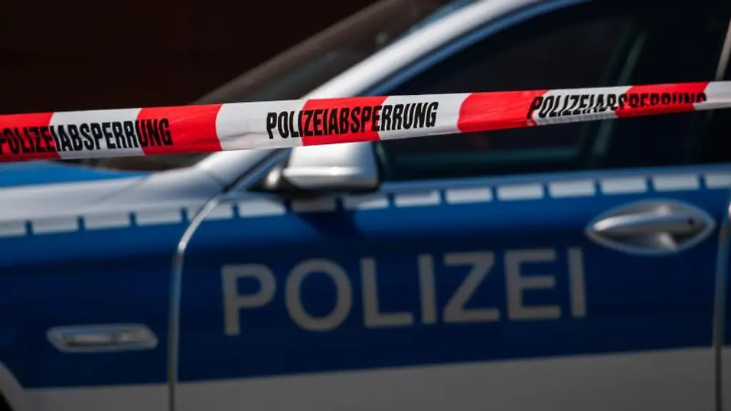 Ein-Polizeiauto-steht-hinter-einem-Absperrband-der-Polizei