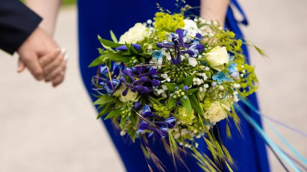 Ein-Brautpaar-haelt-sich-nach-der-Trauung-an-den-Haenden