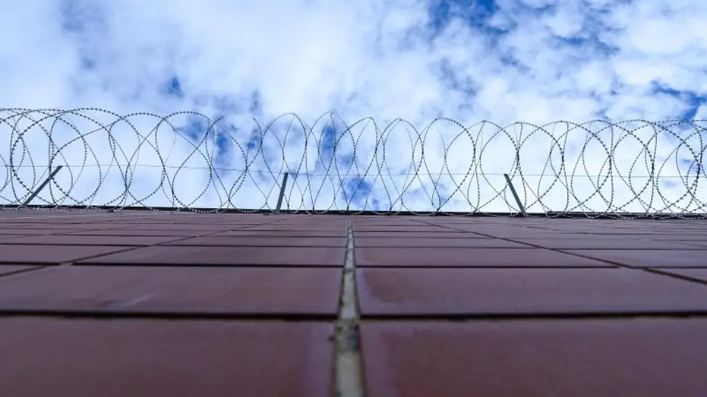 Stacheldrahtzaun-haengt-an-einer-Mauer-in-einer-Justizvollzugsanstalt