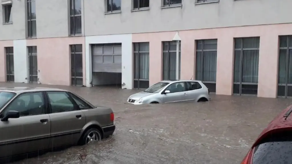 Nach-einem-Unwetter-mit-Starkregen-stehen-Autos-auf-einem-Parkplatz-im-Wasser