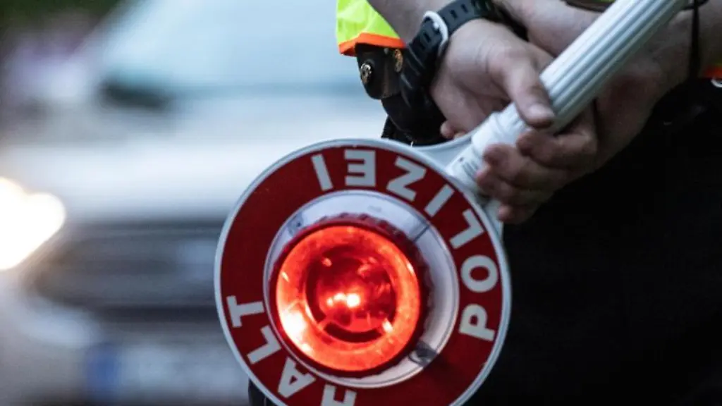 Ein-Polizist-haelt-an-einer-Kontrollstelle-eine-Winkerkelle-in-der-Hand
