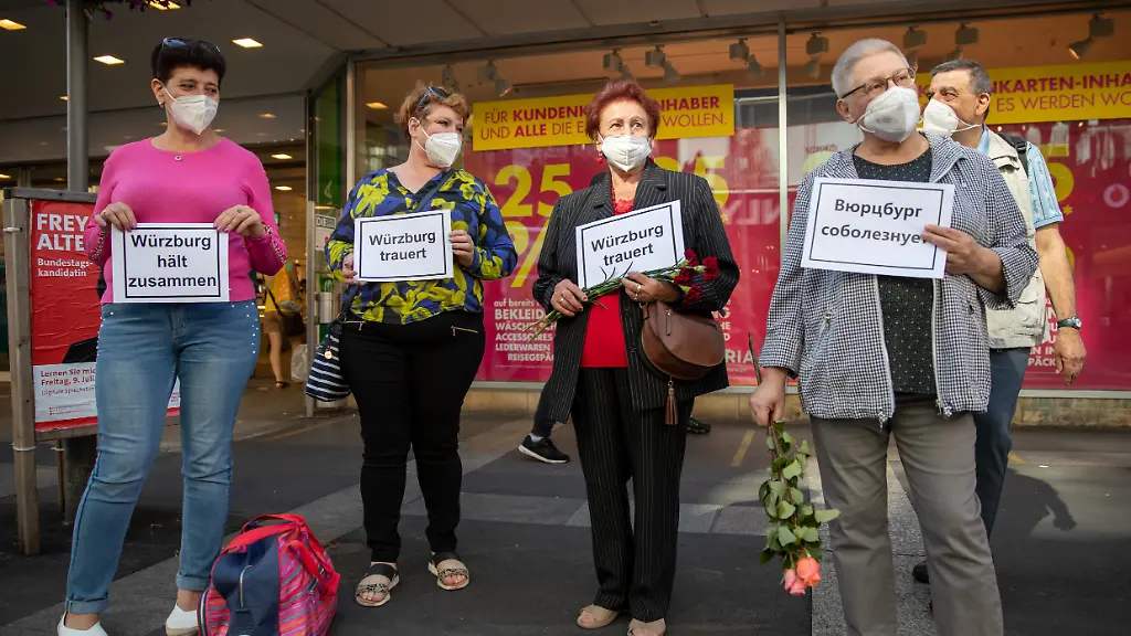 Menschen-halten-Blumen-in-den-Haenden-und-Schilder-mit-den-Aufschriften-Wuerzburg-trauert-und-Wuerzburg-haelt-zusammen-auch-auf-Englisch-Arabisch-und-in-anderen-Sprachen