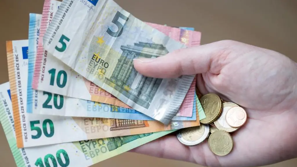 Eine-Frau-haelt-Geldscheine-und-Muenzen-in-der-Hand