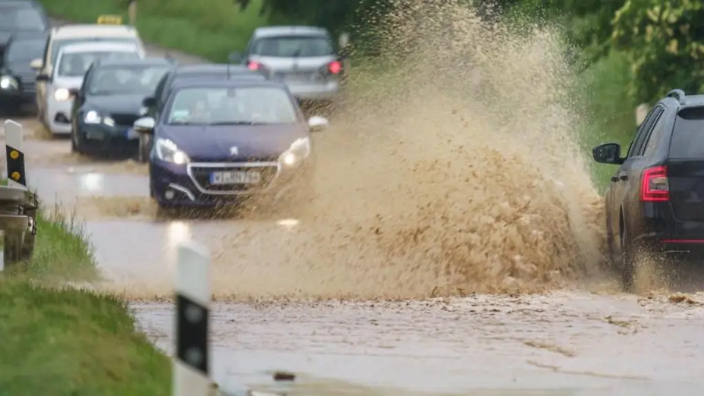 Fahrzeuge-fahren-nach-einem-starkem-Regen-ueber-eine-ueberspuelte-Landstrasse
