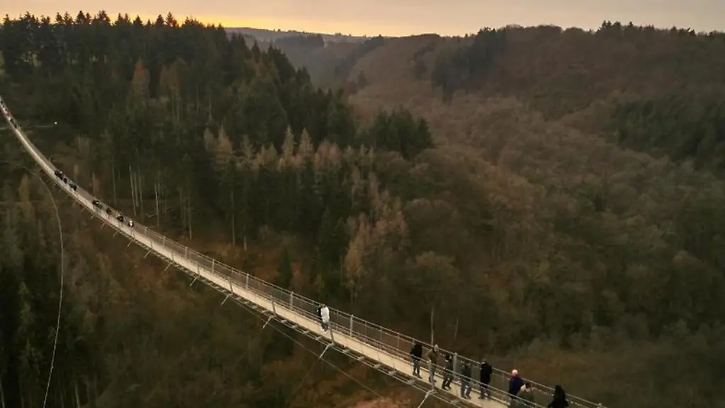 Besucher-gehen-auf-der-Haengeseilbruecke-Geierlay-hoch-ueber-einem-Mosel-Seitental-im-Hunsrueck