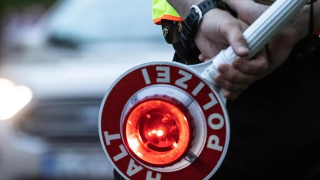 Ein-Polizist-haelt-an-einer-Kontrollstelle-eine-Winkerkelle-in-der-Hand
