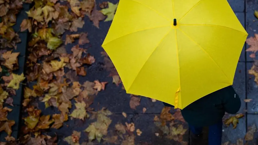 Eine-Person-laeuft-mit-einem-Regenschirm-auf-einem-Gehweg