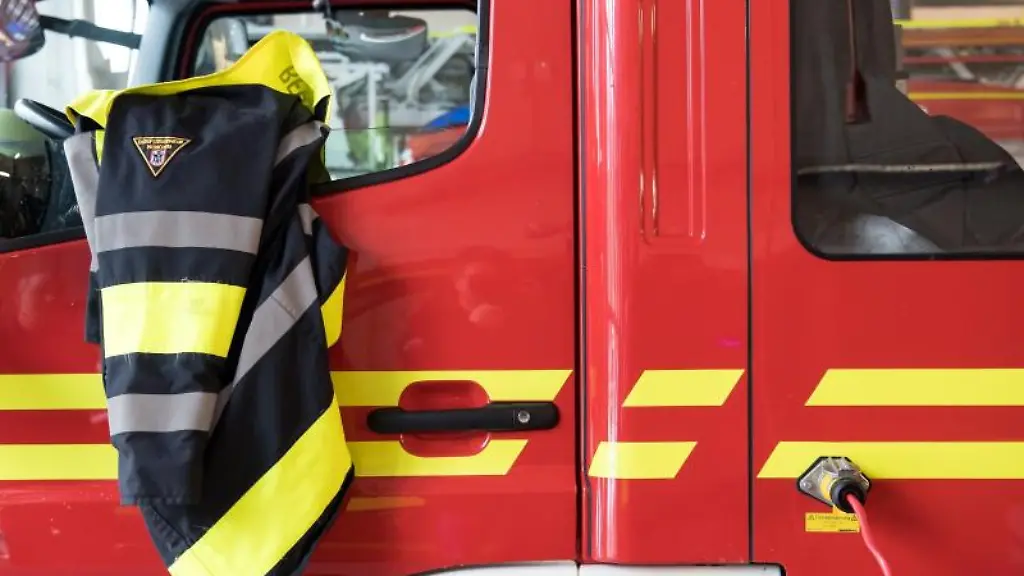 Eine-Feuerwehrjacke-der-Berufsfeuerwehr-Muenchen-haengt-an-einem-Feuerwehrfahrzeug