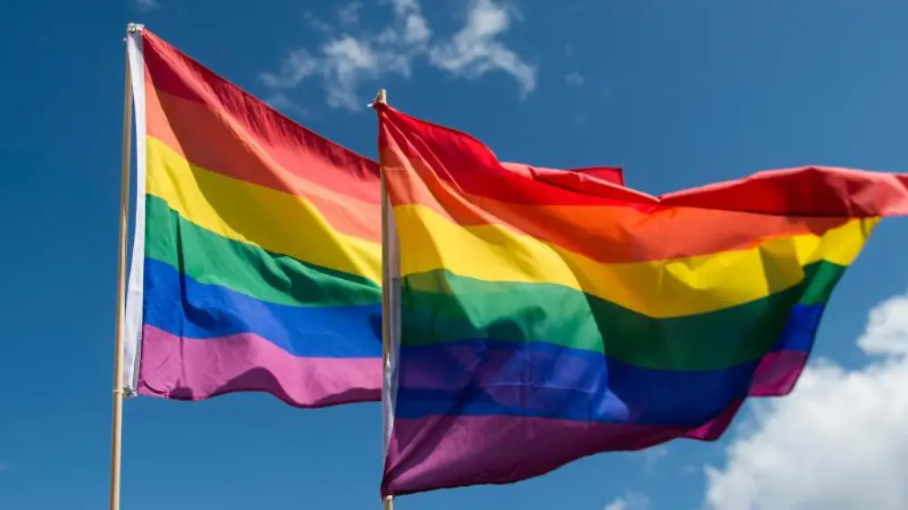 Regenbogenfahnen-wehen-vor-einem-leicht-bewoelkten-Himmel