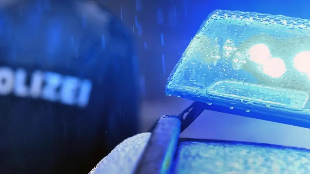 Ein-Polizist-steht-vor-einem-Streifenwagen-mit-Blaulicht