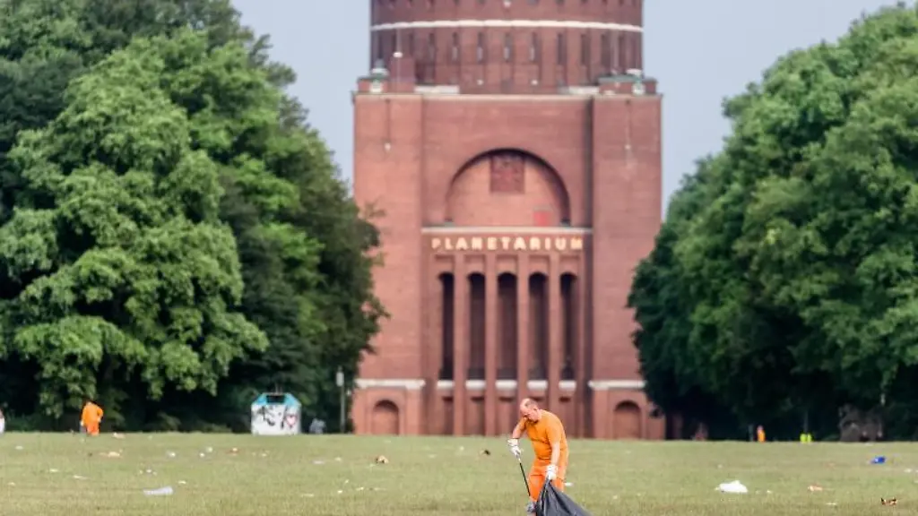 Ein-Mitarbeiter-der-Stadtreinigung-entfernt-am-fruehen-Morgen-den-Muell-im-Stadtpark