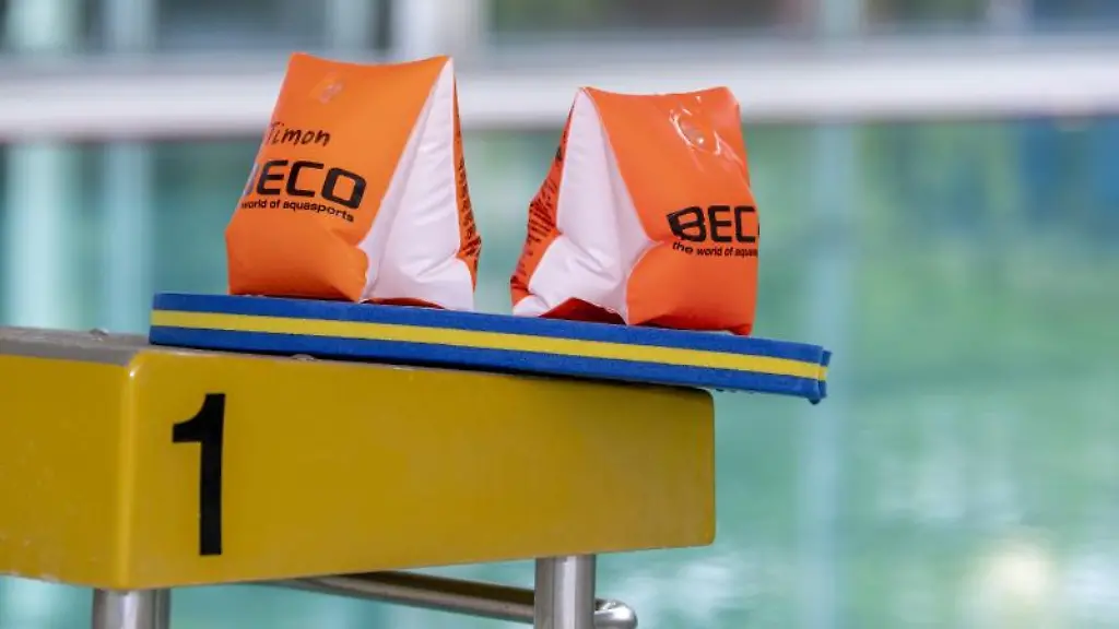 Zwei-Schwimmfluegel-und-ein-Schwimmbrett-liegen-auf-einem-Startblock