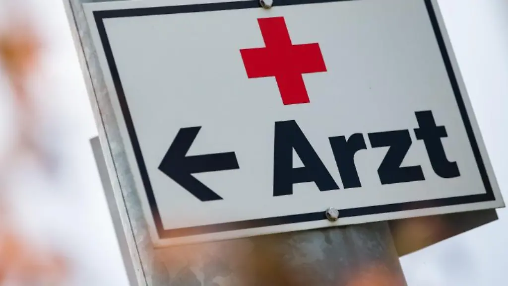 Ein-Schild-mit-der-Aufschrift-Arzt-haengt-an-einer-Strassenlaterne