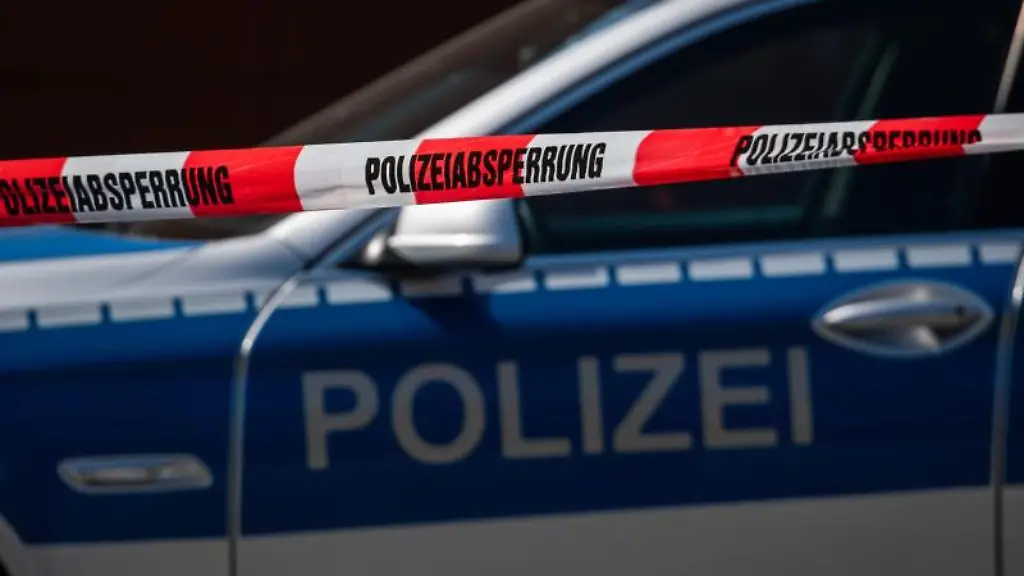 Ein-Polizeiauto-steht-hinter-einem-Absperrband-der-Polizei