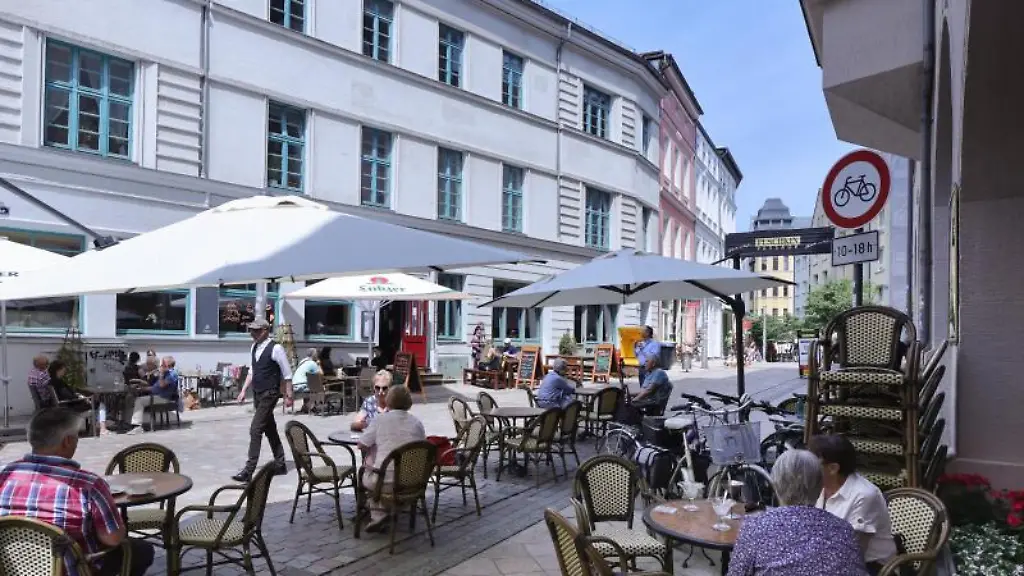 Passanten-geniessen-in-einem-Strassencafe-in-Schwerin-das-sommerlichem-Wetter