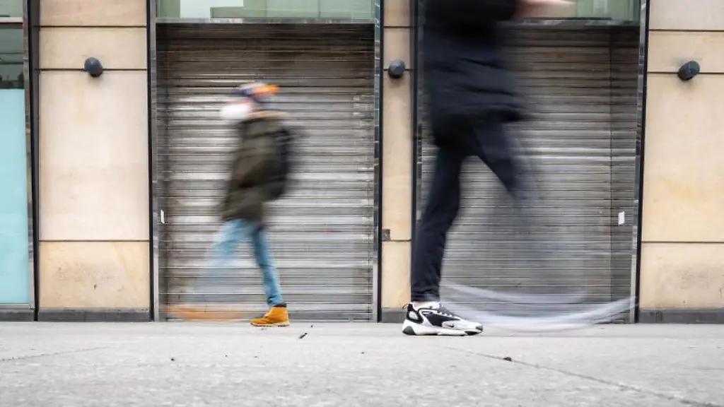 Zwei-Passanten-gehen-an-einem-aufgegebenen-Geschaeft-vorbei