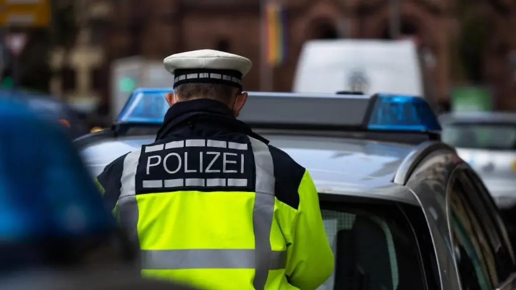 Ein-Polizeibeamter-steht-zwischen-zwei-Einsatzfahrzeugen-der-Polizei