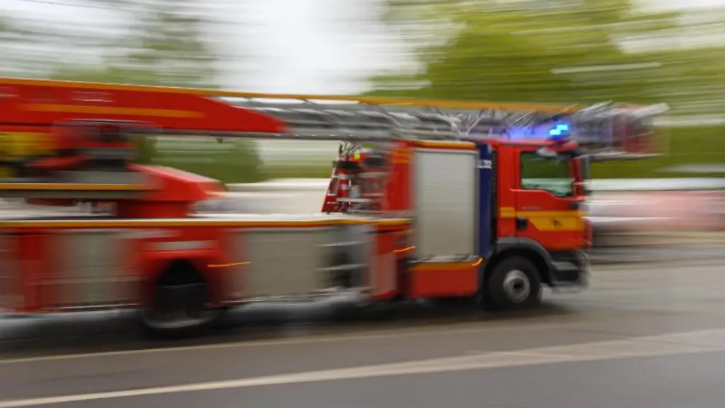 Ein-Feuerwehrfahrzeug-mit-Drehleiter-faehrt-zu-einem-Einsatz