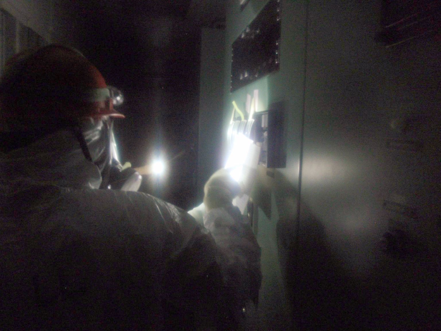 Männer mit Atemschutzmasken und Gummihandschuhen hasten durch die Dunkelheit. 