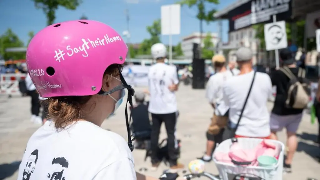 Eine-Frau-steht-mit-einem-Helm-auf-dem-saytheirnames-steht-auf-der-Kundgebung-nach-der-Fahrradsternfahrt-Stern-fuer-Hanau-zur-Erinnerung-an-den-rechtsterroristischen-Anschlag-von-Hanau