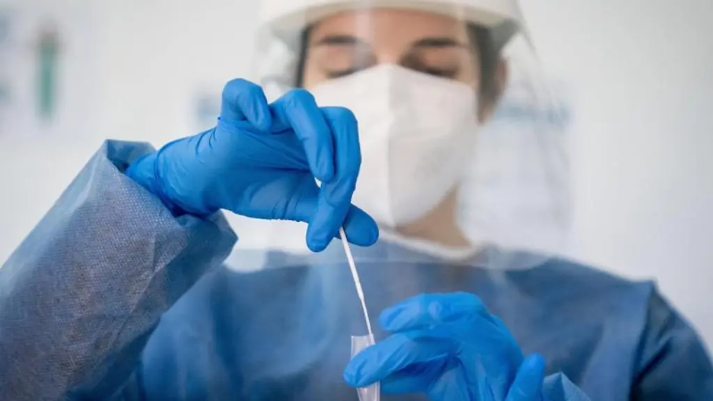 Medizinisch-geschultes-Personal-legt-das-Wattestaebchen-von-einem-Corona-Schnelltest-in-eine-Loesung